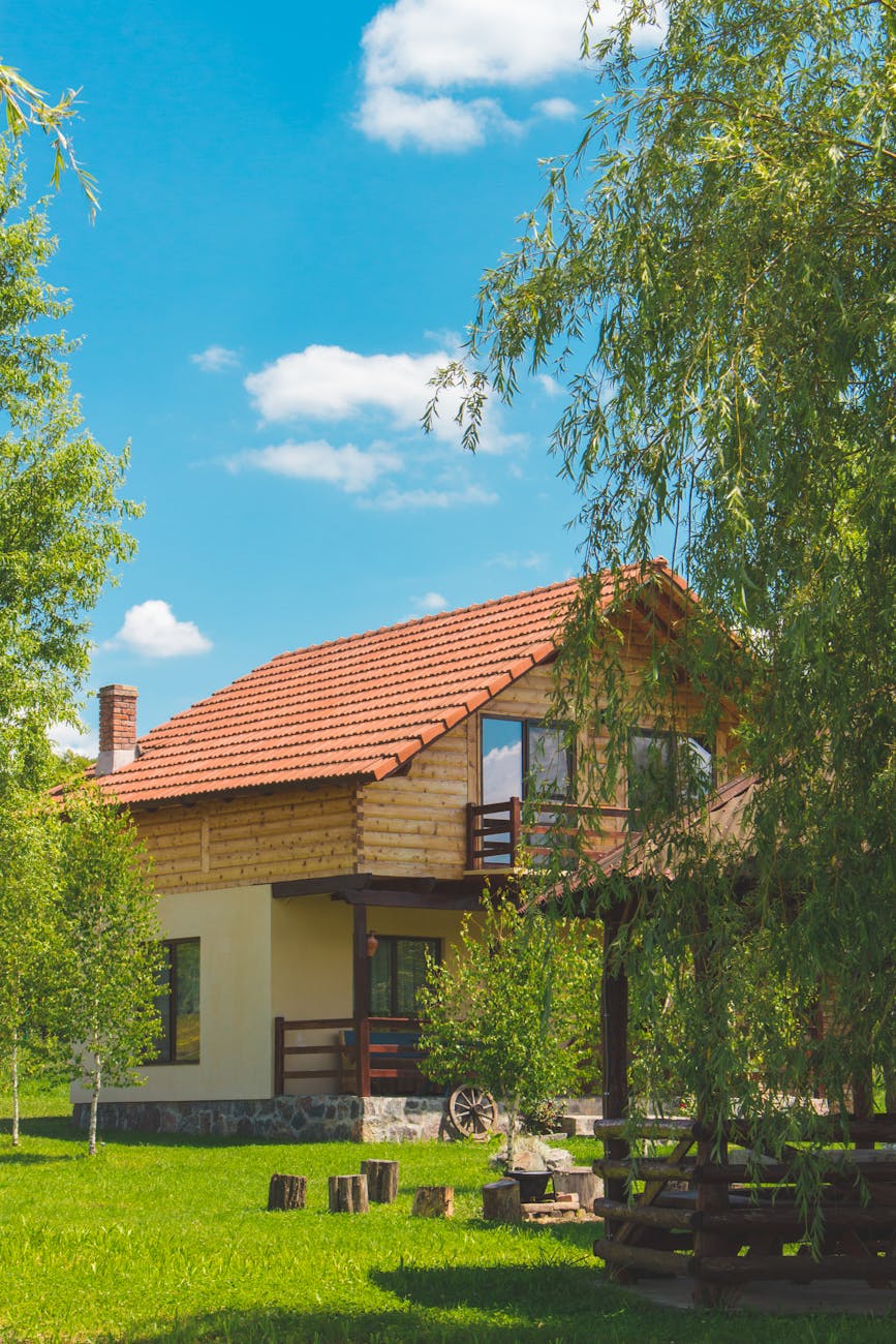 brown and beige painted house surrounded by trees and grass field