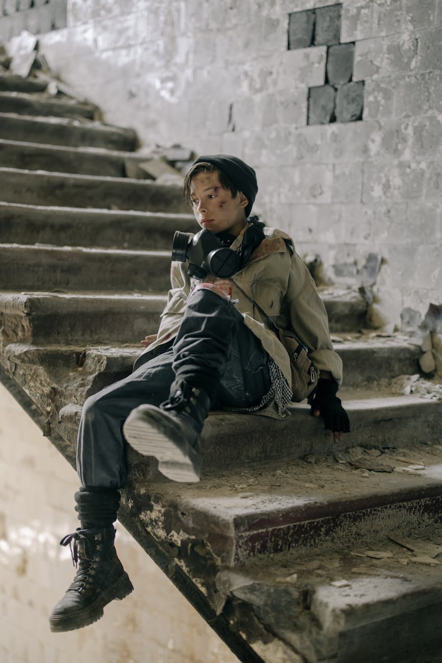 boy in brown jacket sitting on concrete staircase