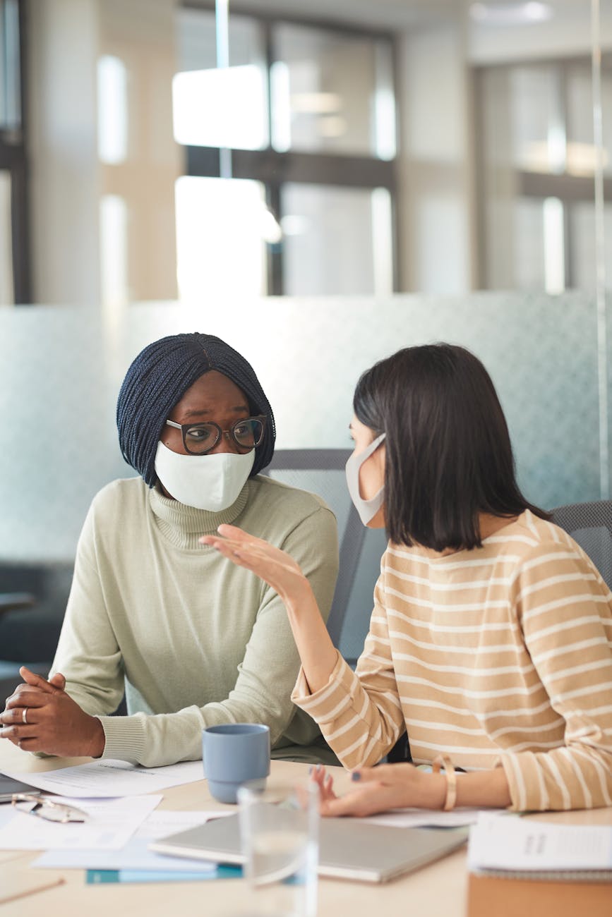 woman in face masks talking in the office